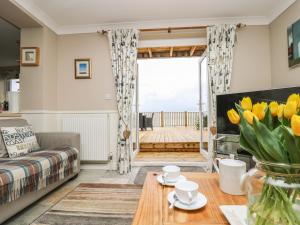 uma sala de estar com um sofá e uma mesa com tulipas amarelas em Pink House em Mevagissey
