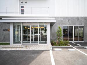 川越的住宿－Super Hotel Saitama Kawagoe，停车场内有玻璃门的建筑