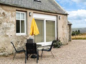 a table and chairs with a yellow umbrella in front of a house at The Auld Kirk in Forsinain