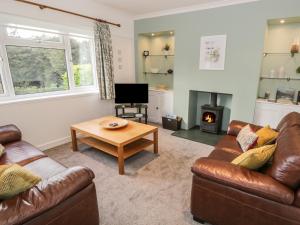 a living room with two couches and a table and a fireplace at Thompson Cottage in Troutbeck