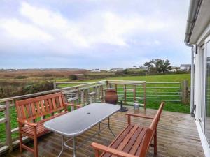 a patio with a table and two chairs on a deck at Ty Woods Cottage in Rhoscolyn
