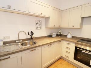 a kitchen with white cabinets and a sink at Foxes Den in Thornton