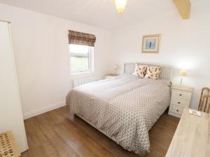 a white bedroom with a bed and a window at Foxes Den in Thornton