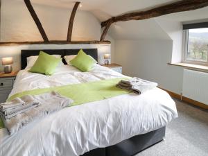 ein Schlafzimmer mit einem großen weißen Bett mit grünen Kissen in der Unterkunft Bryndan in Machynlleth