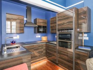 テンビーにあるApartment 3の青い壁と木製のキャビネット付きのキッチン