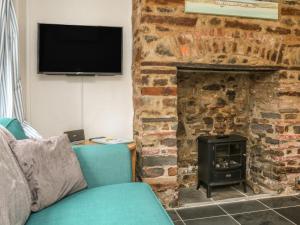 a living room with a stone fireplace and a blue couch at Willets Cottage in Bideford