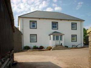 a large white house with blue windows and a driveway at Homestone Farm in Drumlemble