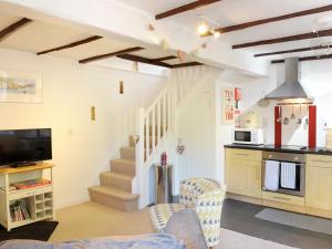 een keuken en woonkamer met een bank en een tv bij Hele Stone Cottage in Launceston