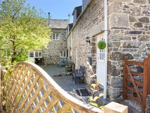 a wooden bench in front of a stone building at Hele Stone Cottage in Launceston