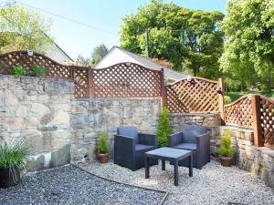 een patio met 2 stoelen en een tafel naast een stenen muur bij Hele Stone Cottage in Launceston +4 foto's