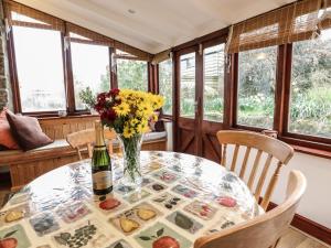 a table with a vase of flowers and a bottle of wine at Brunnion House in Hayle