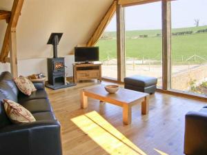 a living room with a couch and a table and a fireplace at Shepherd's Hut in Blandford Forum