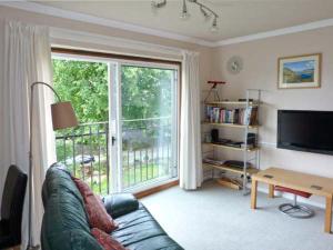 a living room with a couch and a sliding glass door at Baytree Apartment in Grange Over Sands