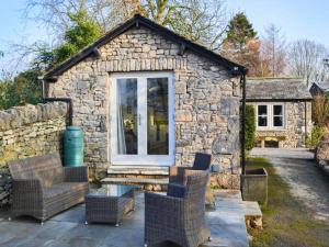 a stone house with chairs and a window at The Potting Shed in Carnforth