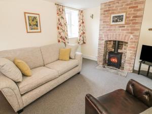 Bear's Cottage في South Littleton: غرفة معيشة مع أريكة ومدفأة