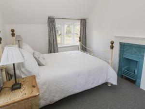 ein Schlafzimmer mit einem weißen Bett und einem Fenster in der Unterkunft Bear's Cottage in South Littleton