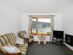 a living room with a couch and a tv and a window at The Ben in Leckmelm