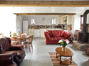 ein Wohnzimmer mit einem roten Sofa und einer Küche in der Unterkunft Bushmills in Bacton