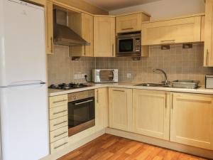 uma cozinha com armários de madeira e electrodomésticos de aço inoxidável em 4 Bredon Court em Newquay