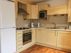 Una cocina con gabinetes de madera y electrodomésticos de acero inoxidable. en 4 Bredon Court, en Newquay