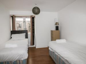 Duas camas num quarto com paredes brancas e uma janela em 4 Bredon Court em Newquay