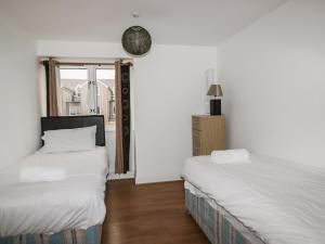 Dos camas en una habitación con paredes blancas y una ventana. en 4 Bredon Court, en Newquay