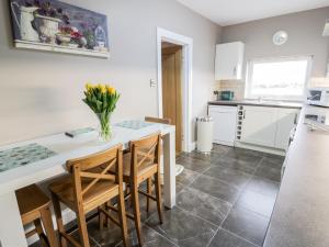 a kitchen with a table with chairs and a vase of flowers at Longforth Farm Cottage in Gillespie