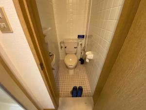a bathroom with a toilet and a pair of blue shoes at Second Habor Beach House in Naha