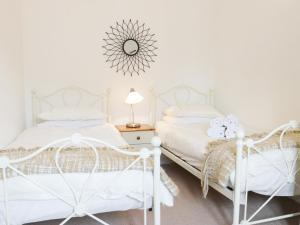 two white beds in a white bedroom with a mirror at Acorn Cottage 1 in Petton