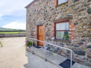 a stone building with a wooden door and a window at Muncaster View in Drigg
