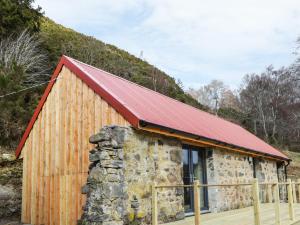 a barn with a red roof and a stone wall at East Craigdhu Cow Byre in Beauly