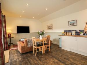 a kitchen and a living room with a table and chairs at East Craigdhu Cow Byre in Beauly
