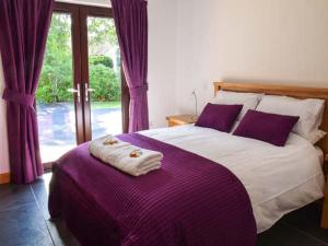 a bedroom with a large bed with purple sheets at Little Chestnut in Muir of Ord