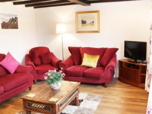 a living room with two red couches and a tv at Nant-Isa in Shelve
