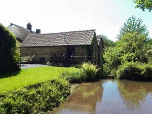 una casa vieja con un estanque delante de ella en The Mill, en Bicknoller