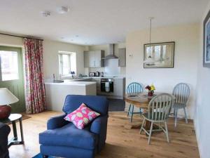 a living room with a blue couch and a kitchen at Ham's House in Coreley