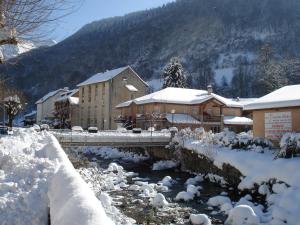 most nad rzeką z budynkami pokrytymi śniegiem w obiekcie Résidence des 3 Césars w mieście Aulus-les-Bains