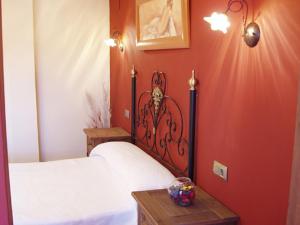 a bedroom with a bed with a red wall at Hotel El Yedron in Aldeanueva de la Vera