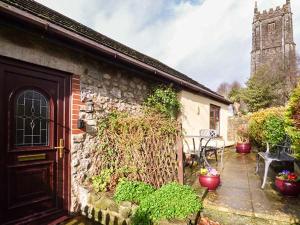 a stone house with a door and a table and bench at Fairwater Mill Cottage in Kingsteignton