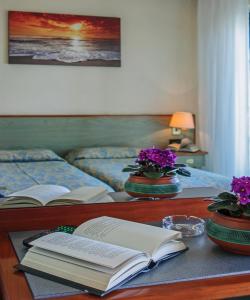 a table with books and flowers on a bed at Hotel Paris in Lido di Camaiore