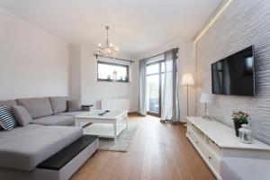 a living room with a couch and a tv at Perła Rentyear Apartments in Gdańsk