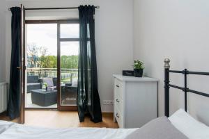 a bedroom with a bed and a sliding glass door at Perła Rentyear Apartments in Gdańsk