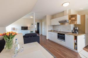 a kitchen with white cabinets and a table with flowers at Hotel Gästehaus Zürn in Wasserburg