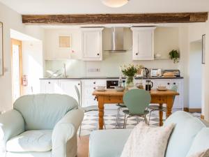 a kitchen with white cabinets and a table with chairs at Salters in Kennerleigh