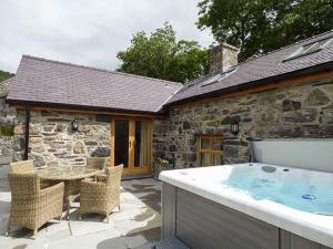 a stone house with a hot tub in front of it at Briws in Llangwm