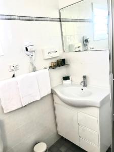 a white bathroom with a sink and a mirror at Kiama Motel 617 in Kiama