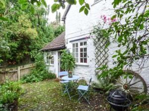 a small white house with a table and chairs in the yard at The Smithy in Leominster +5 photos