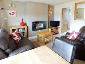 sala de estar con 2 sofás de cuero y TV en Swallows Nest en Coniston