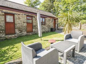 a patio with two chairs and a table and an umbrella at Cosy Cottage in Liskeard