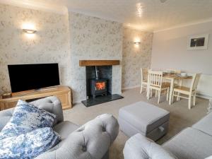 a living room with a couch and a fireplace at Rhos Cottage in Benllech